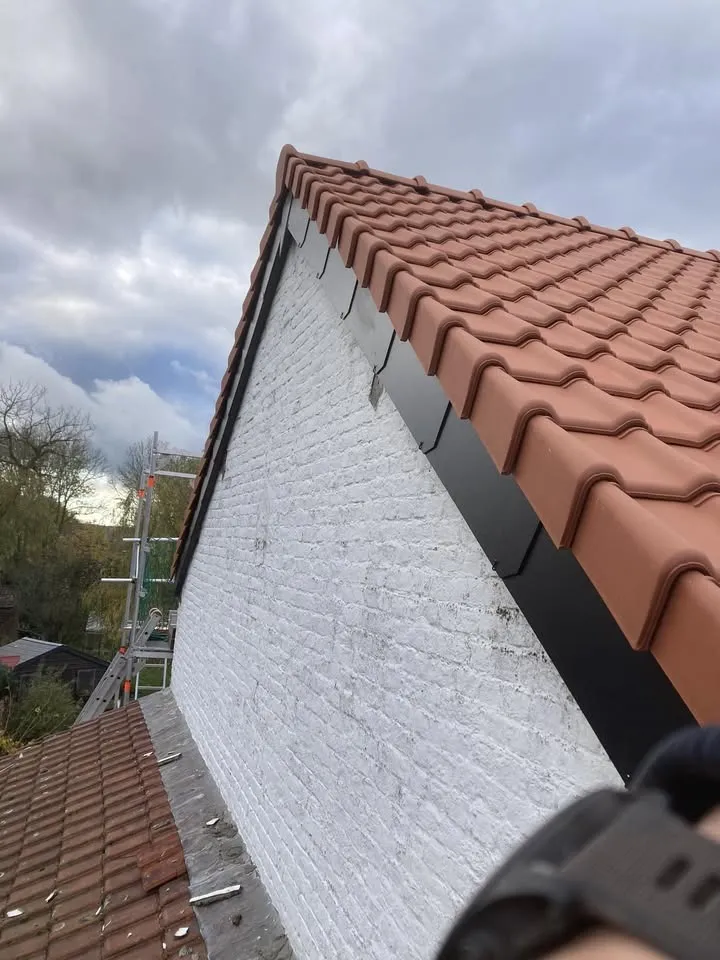 Toiture en tuile terre cuite, vue de profil sur une façade blanche.